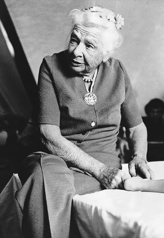 Black and white image of Dr. Ida Rolf with her hands on a client's foot